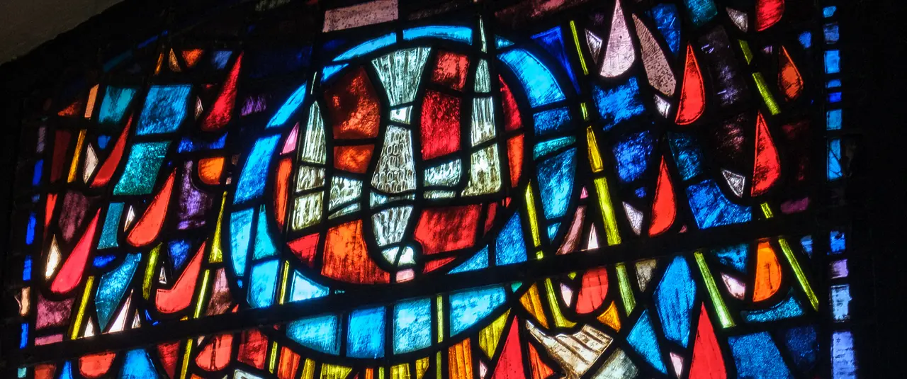 Fenstermosaik in der Luisenkirche. "Pfingst"-Fenster. Mittig eine Taube, die vom Himmel kommt in einem Kreis.