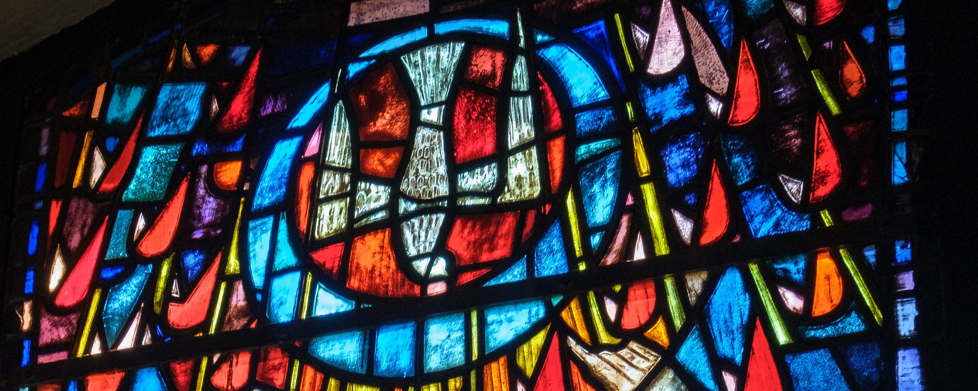 Fenstermosaik in der Luisenkirche. "Pfingst"-Fenster. Mittig eine Taube, die vom Himmel kommt in einem Kreis.
